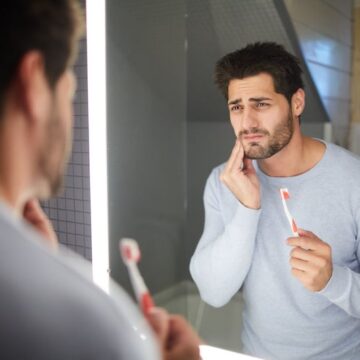 Man brushing his teeth with tooth pain