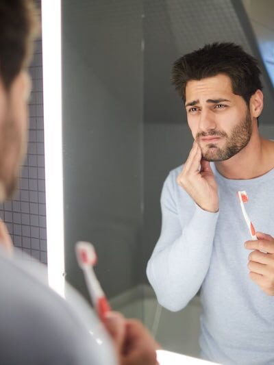 Man brushing his teeth with tooth pain