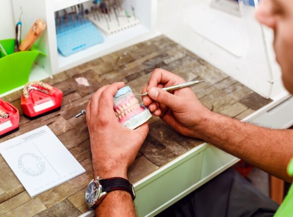 Dentist showing Tooth Extraction Healing White Stuff on a pain of dentures on a desk