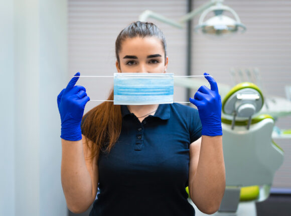 Women holding up mask in dentist office