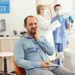 Sick patient complaining about teeth pain while waiting for dentists doctors