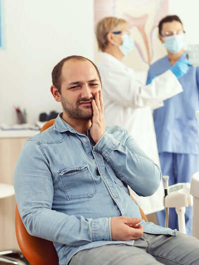 Sick patient complaining about teeth pain while waiting for dentists doctors